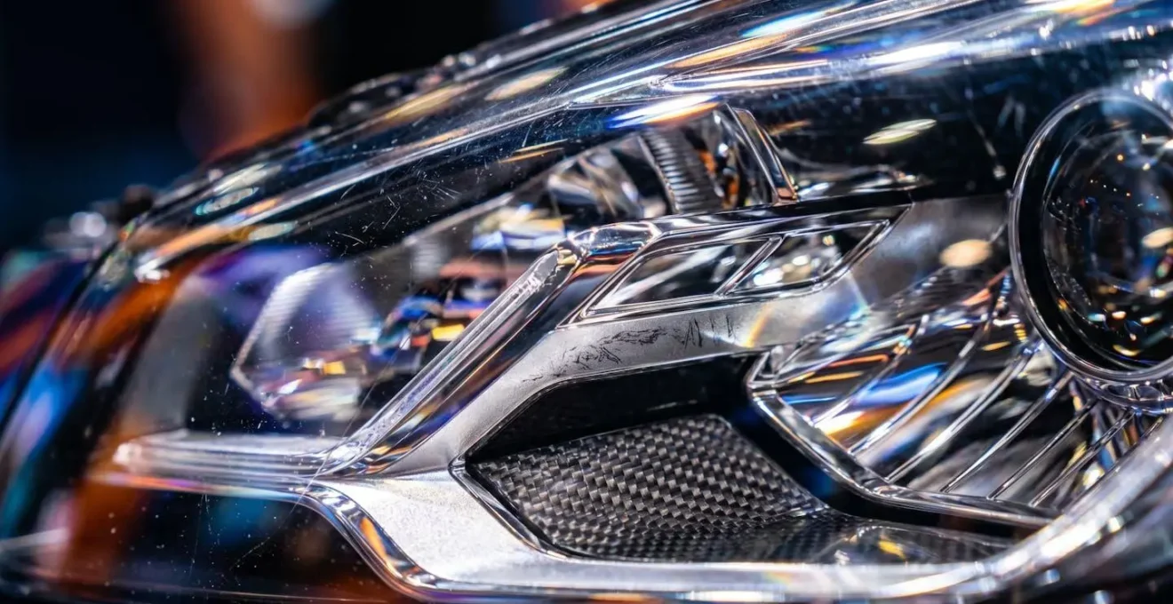 Close-up van autokoplamp met reflecties van beursverlichting